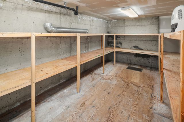Unfinished storage room with rough site-built lumber shelving and concrete walls